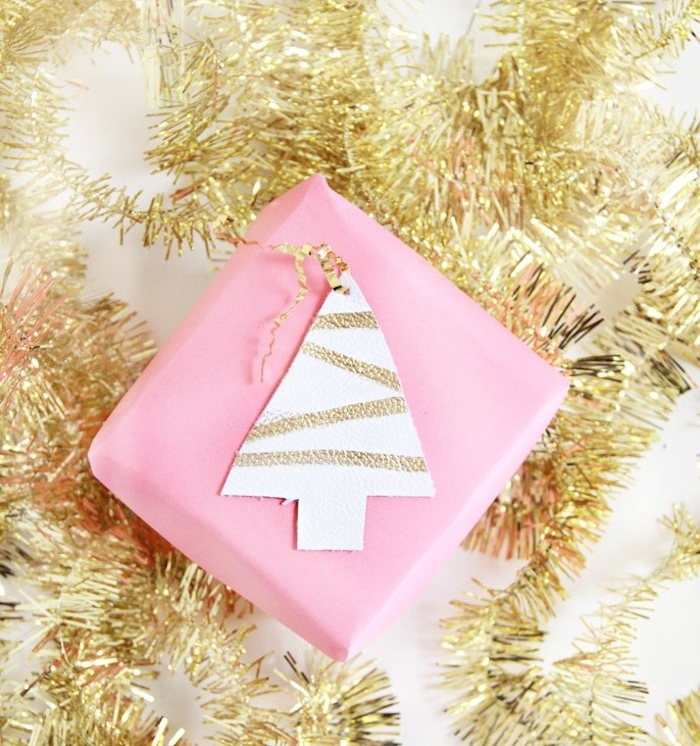 paquet cadeau noel simple en rose avec un motif sapin de noel en cuir décoré de lignes dorées collée dessus