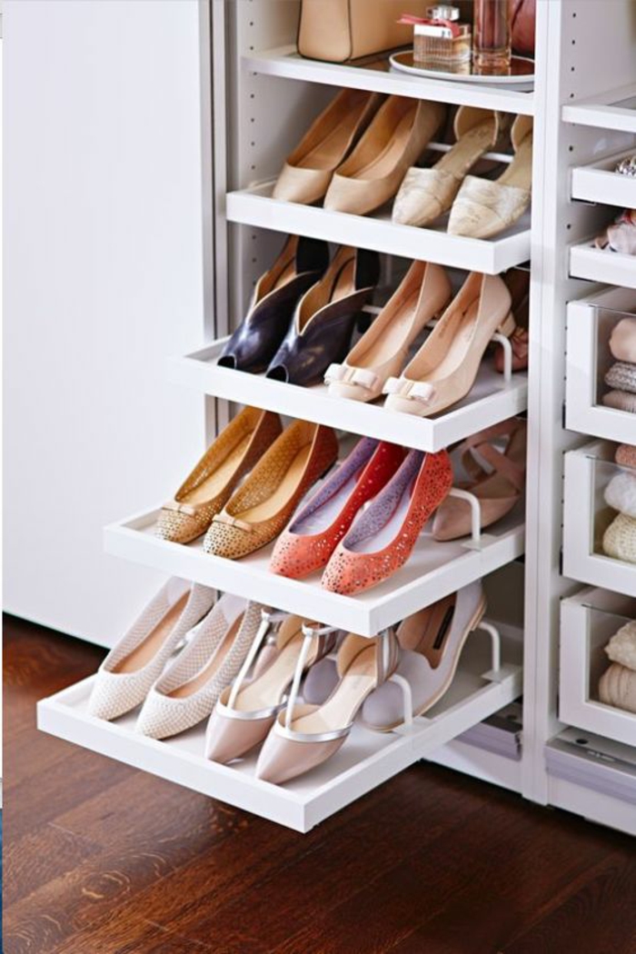 rangement chambre avec des tiroirs coulissants pour les nombreuses paires de chaussures, parquet en couleur cerisier, étagères blanches pour les vêtements 