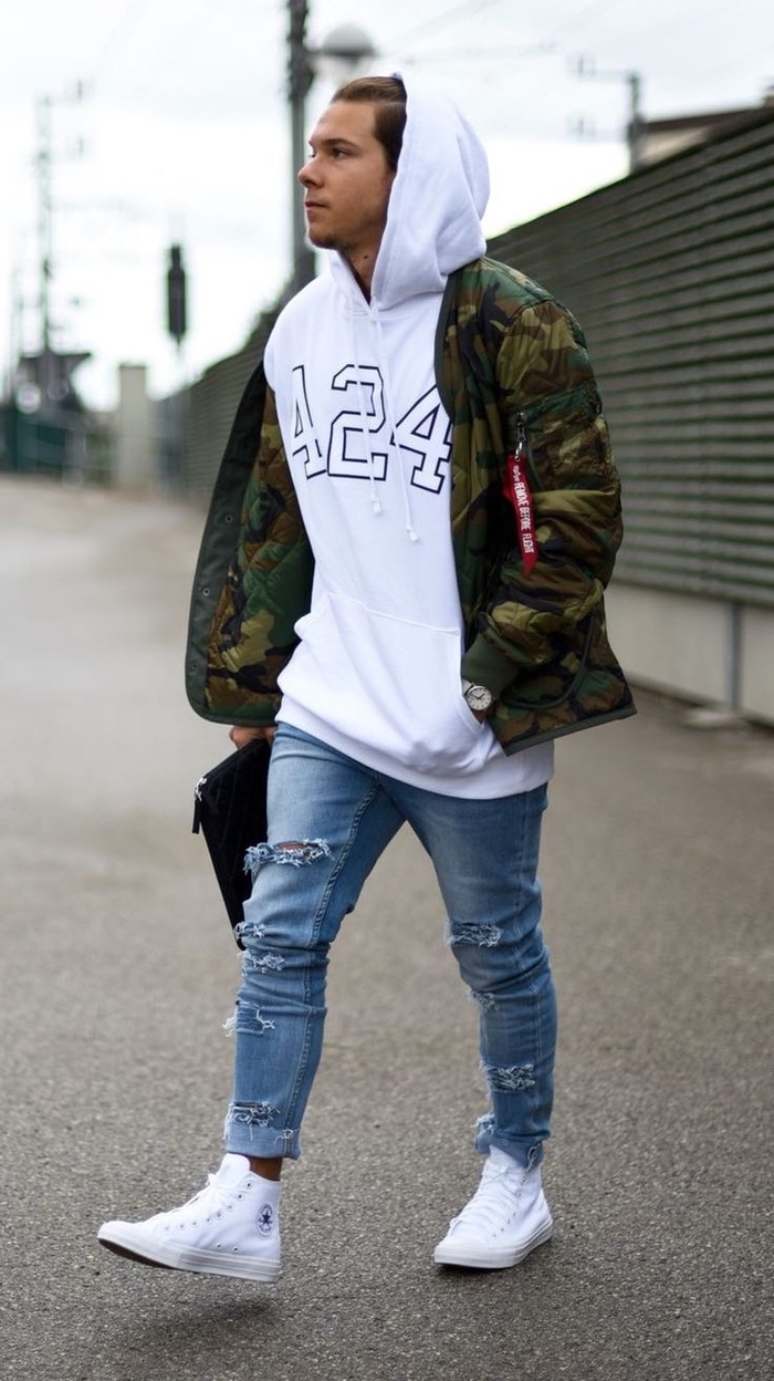 look décontractée à inspiration streetwer qui associe la veste camouflage homme à un sweat à capuche oversize et des jeans déchirés