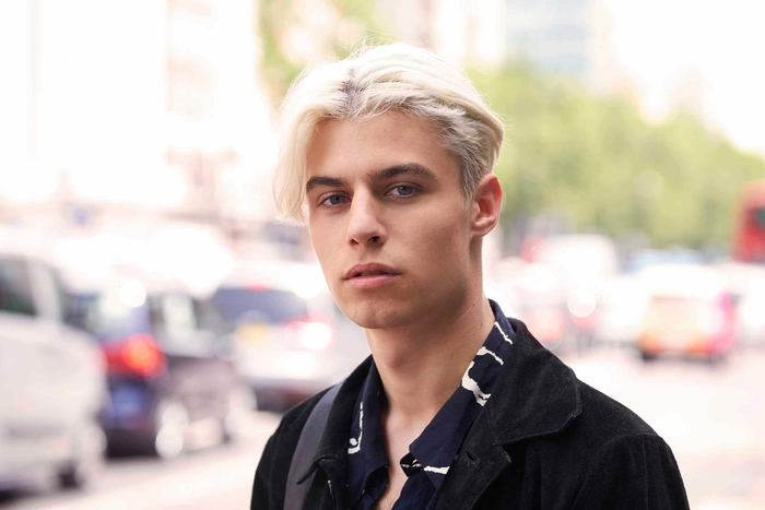 une coupe cheveux homme inspirée des années quatre-vingt-dix avec raie au milieu des cheveux et une coloration blonde