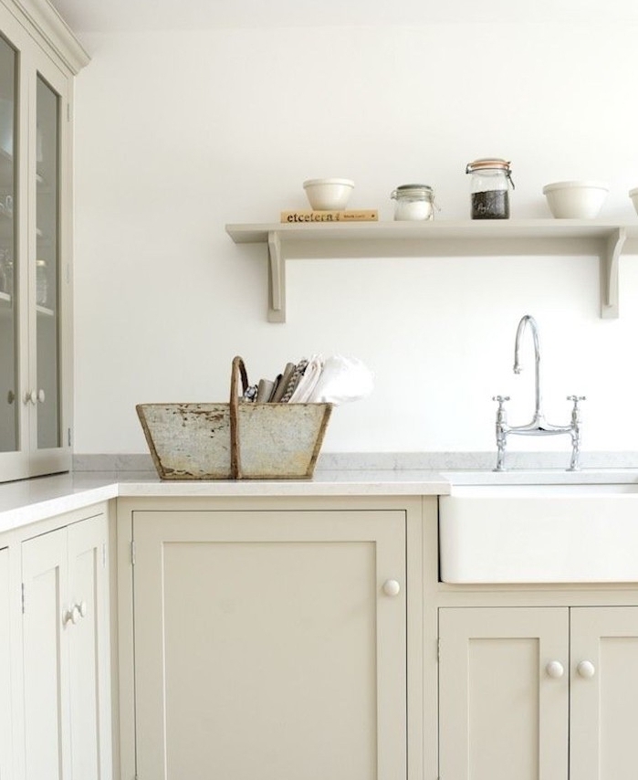 façade cuisine couleur taupe claire avec plan de travail blanc et étagère gris perle, robinetterie grise, vasque à poser blanche, panier en métal rangement vaisselle