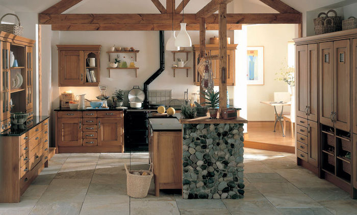 cuisine rustique en bois avec poutres apparente, ilot central bois décoré de pierres, dallage en pierre, vaisselier et meuble cuisine bois