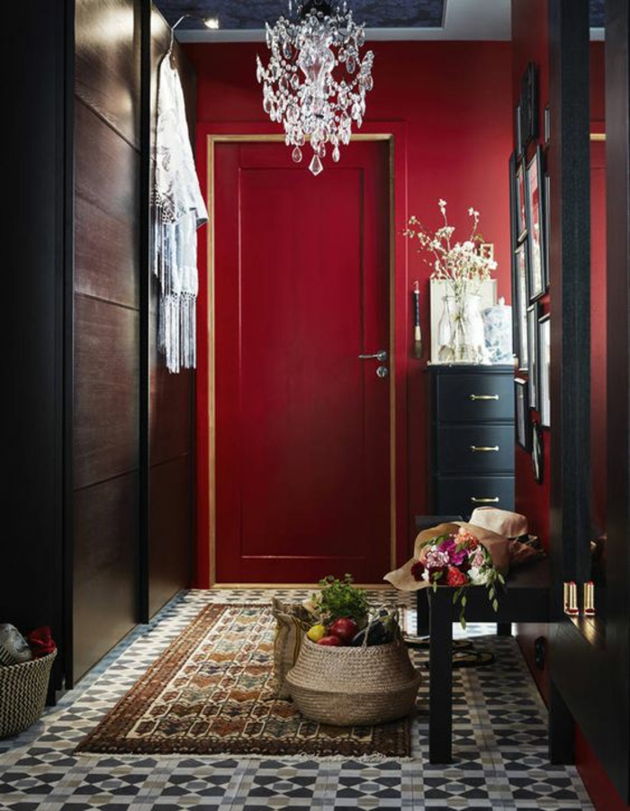 decoration couloir long et etroit en rouge et noir, carrelage en gris, blanc et beige, grand miroir carré en cadre noir, banc noir, meuble avec quatre tiroirs, luminaire en pampilles en cristal en style baroque