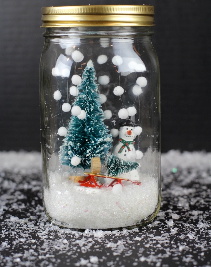 deco de noel fait main avec des bocaux en verre recyclés et des figurines de noël, un globe de neige diy sans eau à fausse neige suspendue au couvercle 