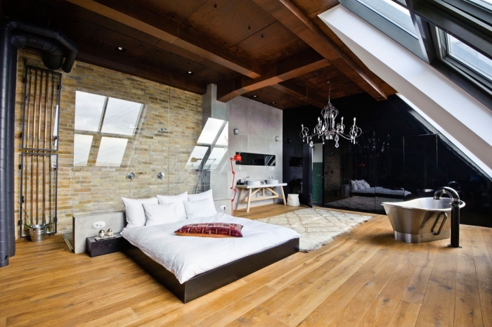 chambre à coucher au grenier avec revêtement murale en pierre et tuyaux apparents de style industriel