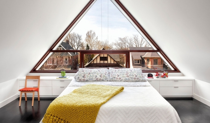 chambre à coucher au grenier décorée simple et moderne avec grand lit et meubles en bois peints en blanc