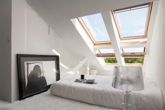 comble aménagé, chambre à coucher blanche aux murs blancs avec lit bas et fenêtre de plafond en bois clair