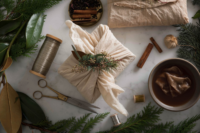 emballage cadeau en tissu blanc cassé et branches de pin vertes, idée décoration simple style champetre chic