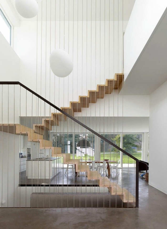 escalier moderne en forme de zig-zag, en couleur beige clair, garde corps en métal noir et des grandes boules blanches sur les murs 