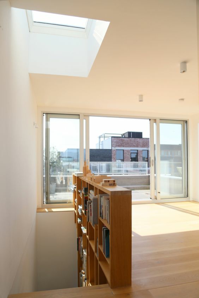 escalier bois escalier moderne escalier design en bois clair avec étagères bibliothèque insérées, maisonnette avec étage supérieur très lumineux, plafond avec fenêtre carrée et une fenêtre avec portes coulissantes pour sortir sur le toit