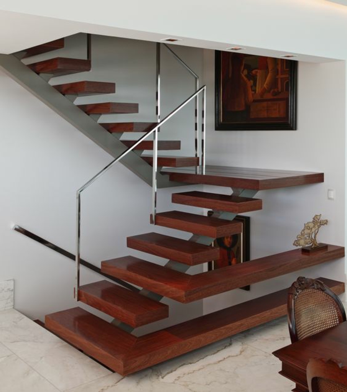 escalier bois avec des marches en couleur cerise, garde corps escalier interieur en métal couleur argent, sol recouvert de carrelage aux motifs marbrés, table et chaises en couleur cerise