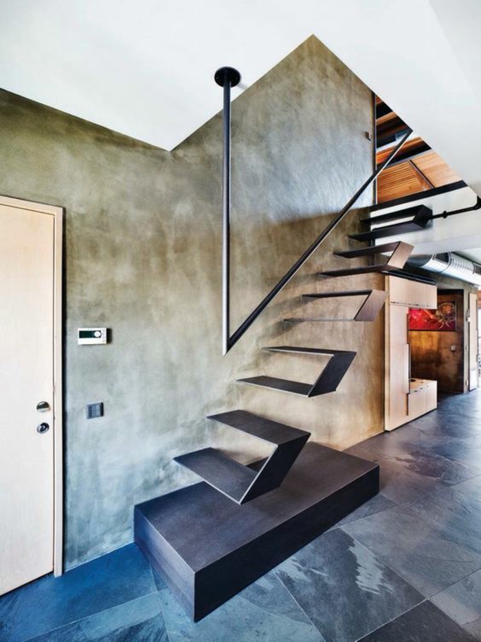 escalier moderne en métal noir avec base solide, marches suspendues sans garde corps, poignée noire en métal, murs gris, sol avec carrelage en nuances noires, grises et blanches
