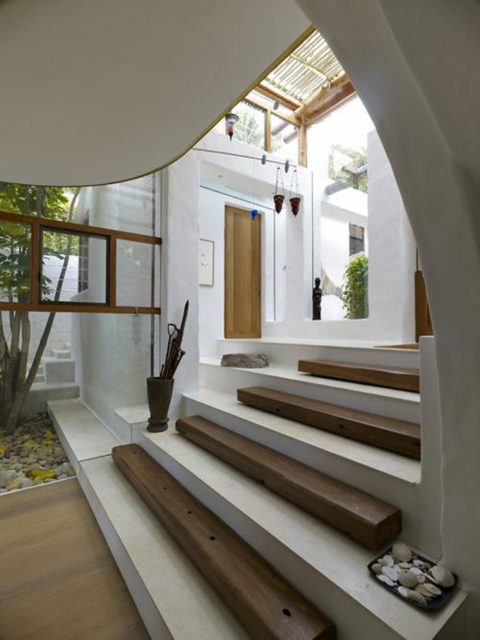 escalier design avec base en blanc et partie en bois couleur foncée, cailloux décoratifs, porte-parapluie, ambiance ethno chic