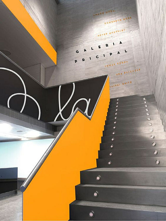 escalier design en gris anthracite et garde corps en jaune dans une galerie d'art, marches illuminées par des petits corps lumineux, disposés de manière régulière par deux sur la longueur de la marche 