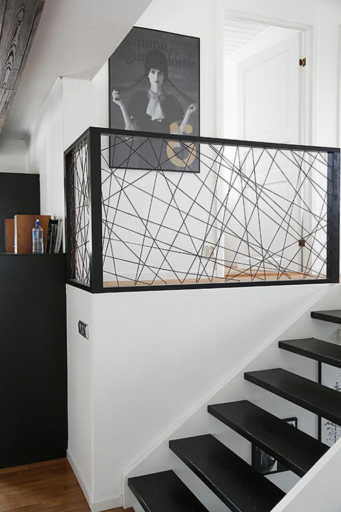 escalier design avec des marches en bois noir garde corps en métal noir avec des effets décoratifs fils fins qui s'entrecroisent 