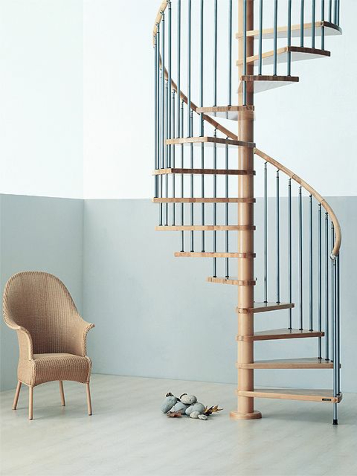 escalier design en forme de coquillage, marches étroites, fauteuil tressé en couleur beige avec des pieds hauts, garde corps en bois noir et beige, effets barreaux fins