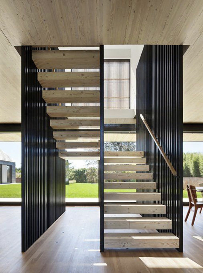 escalier interne, escalier design, en métal noir et escaliers en pierre blanche, plafond en pierre grise, sol recouvert de parquet PVC en nuances beiges et marron clair