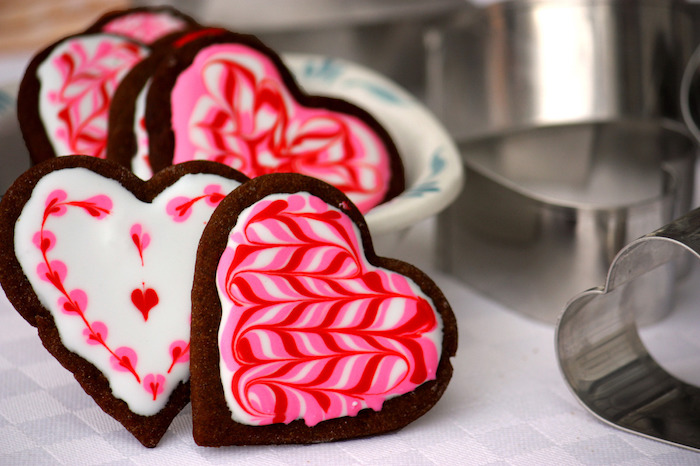 biscuits au chocolat au glacage sucre glace rouge et blanc effet marbre, sablés en forme de coeur pour saint valentin