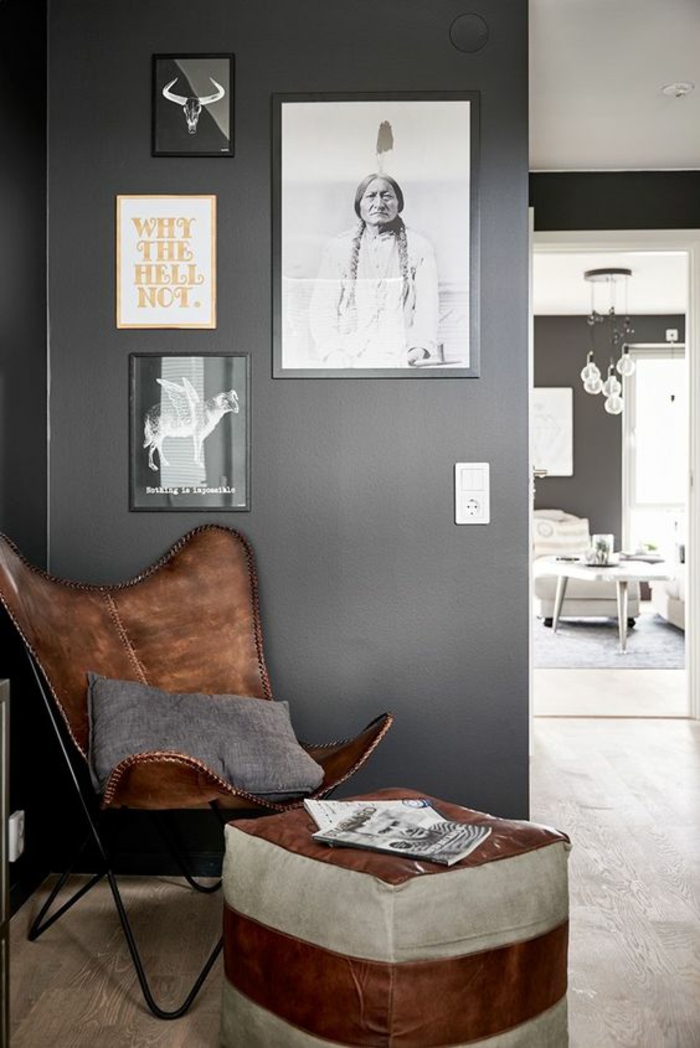 quelle couleur pour un couloir gris anthracite, fauteuil en cuir marron et tabouret en cuir marron et gris, mur en gris avec des photos en cadres noirs, sol recouvert de parquet lisse en PVC