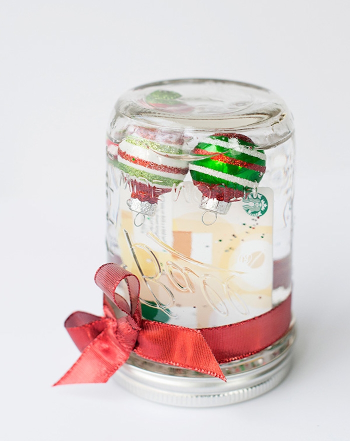 idee cadeau noel ado 15 ans, une boule à neige en verre dans un bocal décoré de ruban rouge et boules de noel à l intérieur