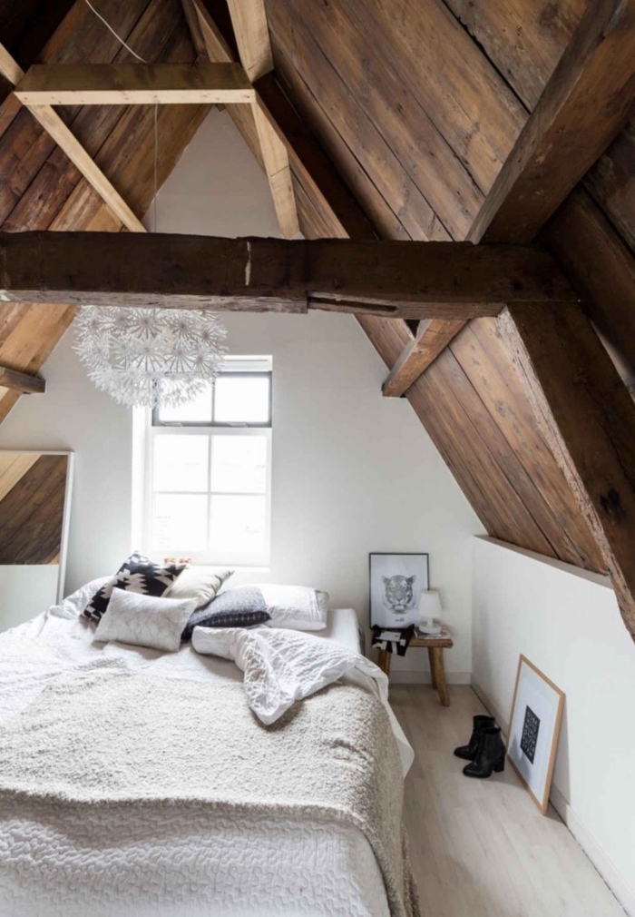ambiance cozy dans une chambre à coucher sous pente avec grand lit bas décoré de plaids doux et coussins