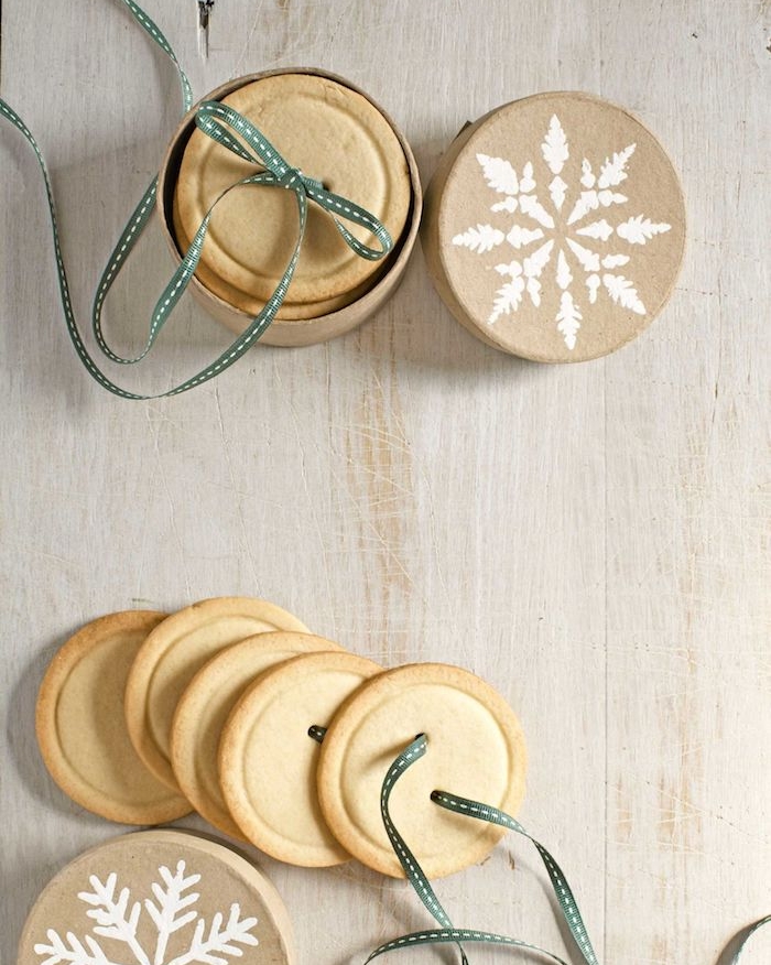 sables de noel en forme de boutons avec un ruban décoratif dans une boîte à cadeau en carton, dessert simple et rapide, idée de cadeau gourmand