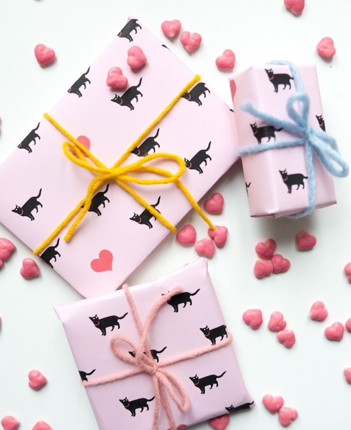 exemple emballage cadeau original en rose à motif chat noir et ficelle de laine jaune, rose ou bleue, bonbons en forme de coeur