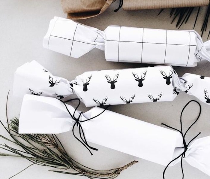 exemple pour emballer un cadeau rond en forme de bonbon, papier blanc à motif rudolphe le renne, ficelle noire, style scandinave