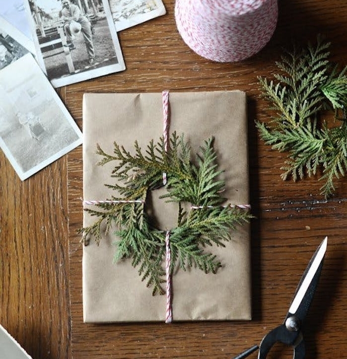 kraft papier cadeau noel avec décoration de couronne de branches vertes et ficelle rouge et blanc
