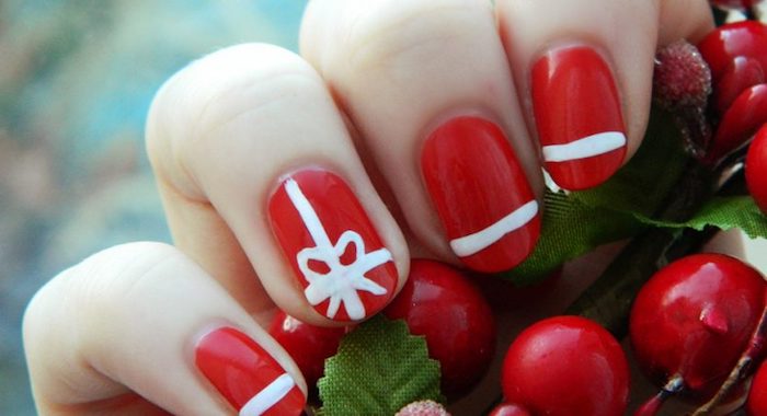 manucure-noel-facile-fond-rouge-avec-des-bandes-blanches-et-ruban-dessinsés-au-pinceau-houx nail art noel facile, un vernis à ongles rouge avec motif lignes blanches et neud de ruban blanc, houx rouge
