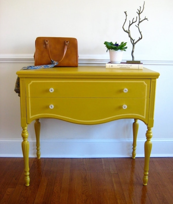 peinture pour meuble jaune, table d appoint repeinte, boutons vintage, sac à manin en cuir, plante verte et livre, parquet marron