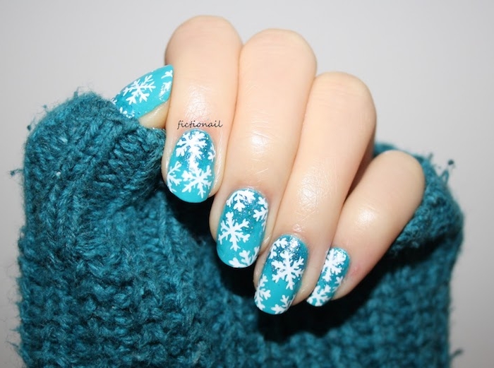 exemple de deco ongles noel, vernis couleur bleue et dessin de flacons de neige blanches, pull bleu