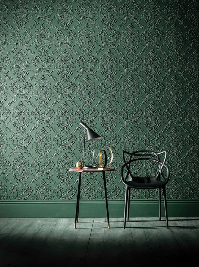 papier peint trompe l'oeil en vert, aux motifs arabesques, avec chaise en métal noir et table ronde avec des pieds hauts en métal noir, lampadaire pour table en métal noir et style industriel