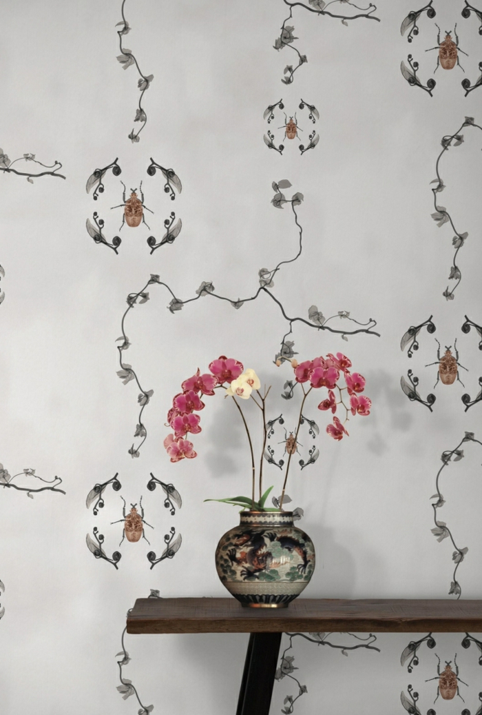 papier peint trompe l'oeil aux motifs insectes et feuilles, mur d'entrée avec table minimaliste avec vase bombée aux motifs chinois, avec des fleurs en rose et blanc