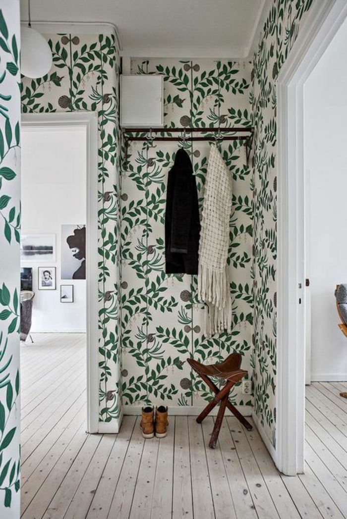 papier peint trompe l'oeil dans une entrée, avec des plantes vertes rampantes, plafond en blanc, porte-manteaux en métal noir