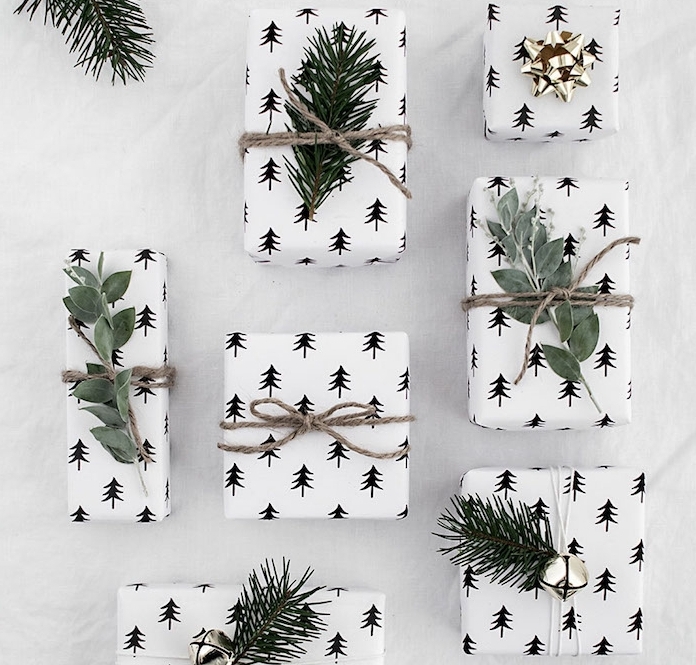 boite emballage cadeau blanc à motif silhouettes de sapins noirs branches vertes de in et ficelle de lin, clochettes et ruban doré