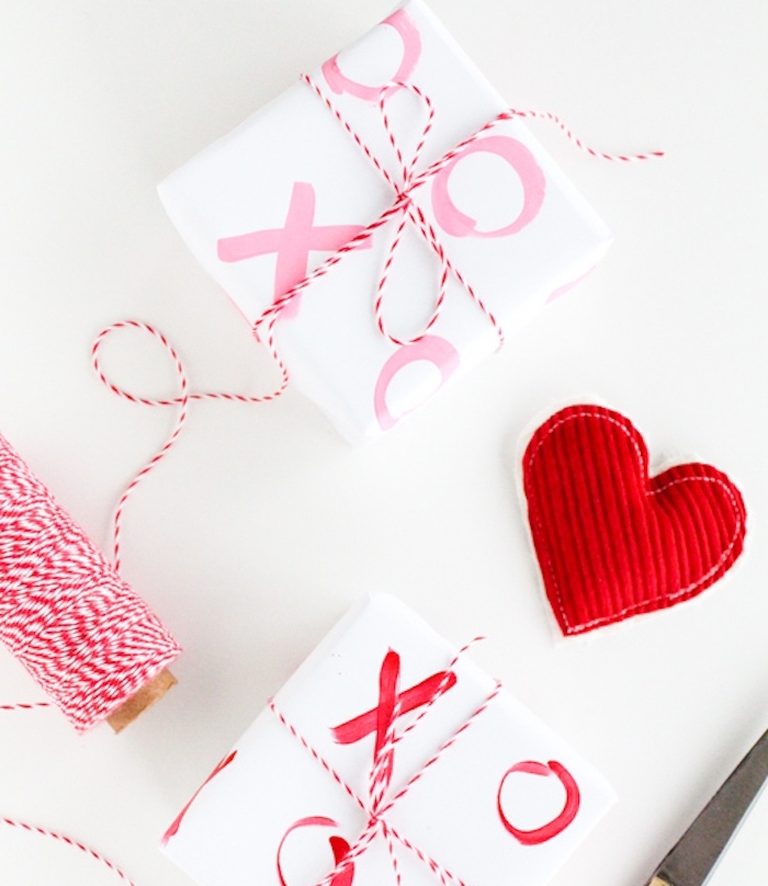 comment emballer un cadeau, papier cadeau original blanc à motif de noel xo xo, ficelle rouge et blanc noué autour, coeur en tissu rouge
