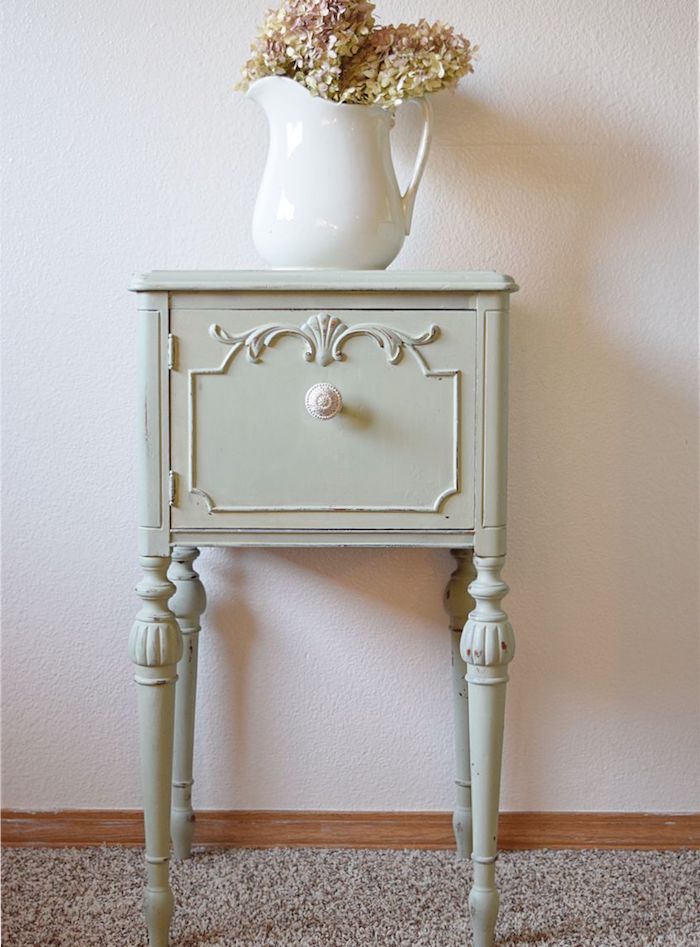 patiner un meuble, petite table d appoint avec tiroir repeinte de vert celadon avec bouton blanc, bouquet de fleurs dans un vase blanc, tapis gris