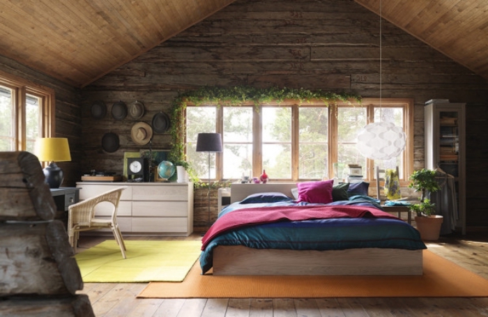 chambre mansardée, cadre de lit en bois avec couverture de lit vert et rouge, bureau en bois peint gris et chaise beige