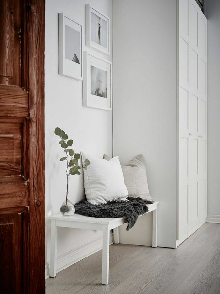 comment decorer un couloir en blanc et gris, trois tableaux en cadre blanc sur le mur blanc, grande armoire blanche avec des motifs décoratifs carreaux, porte en bois marron foncé