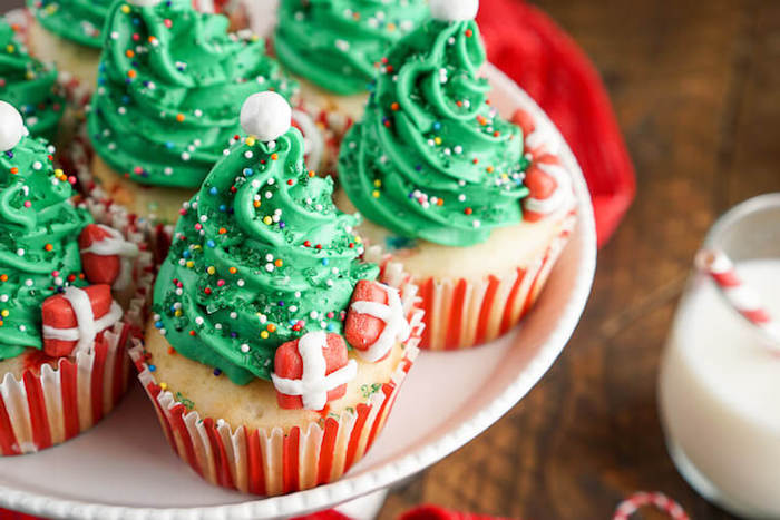 petits gateaux de noel, cupcakes au glaçage vert en forme de sapin de noel et petits cadeaux rouges sucrés