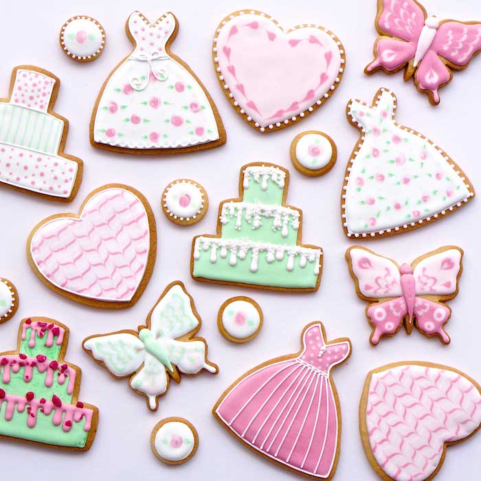 idée comment réaliser une recette glace royale sur des biscuits en formes diverses couverts de glaçage rose, blanc et vert, motif robe, gâteau, papillon et coeur
