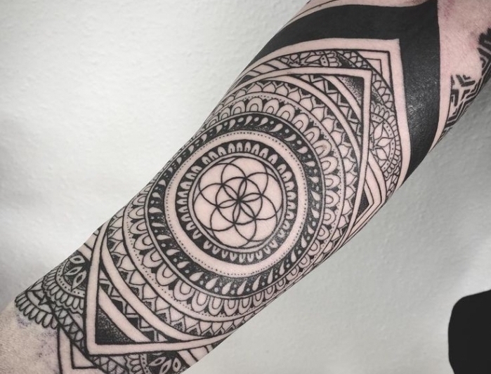 tatouage homme, dessin en encre sur le bras à design mandala aux motifs géométriques
