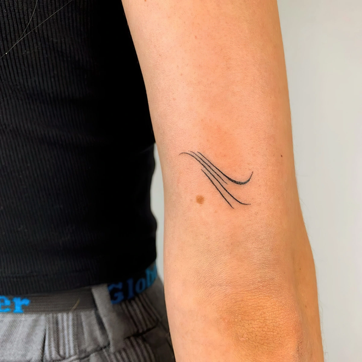 tatouage minimaliste bras femme lignes mouvement courbes