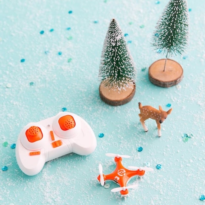 un drone miniature en orange et blanc, petits figurines de sapin de noel et biche, cadeau de noel ado garcon
