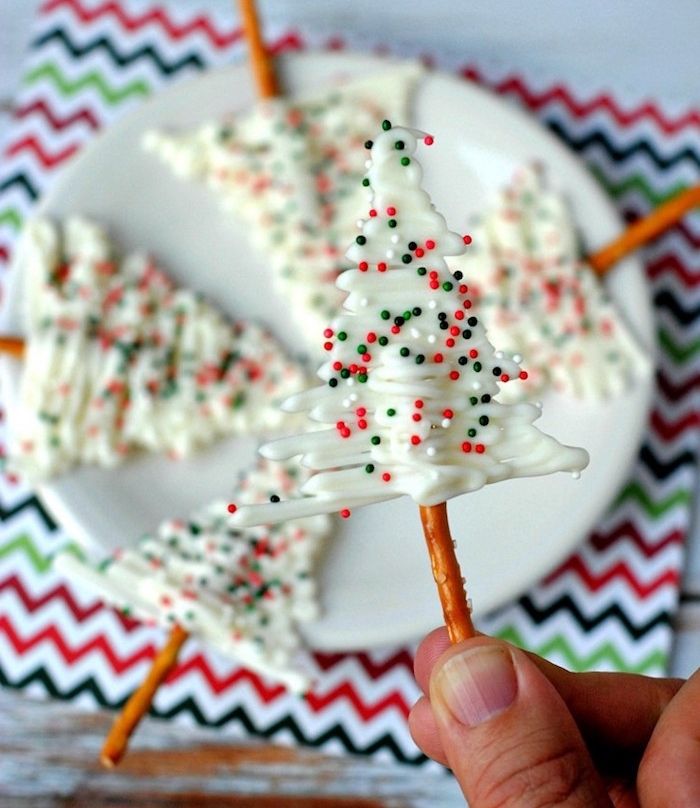 un sapin de noel au chocolat blanc avec decoration de petites billes de sucre, sucette sur une baguette bretzel