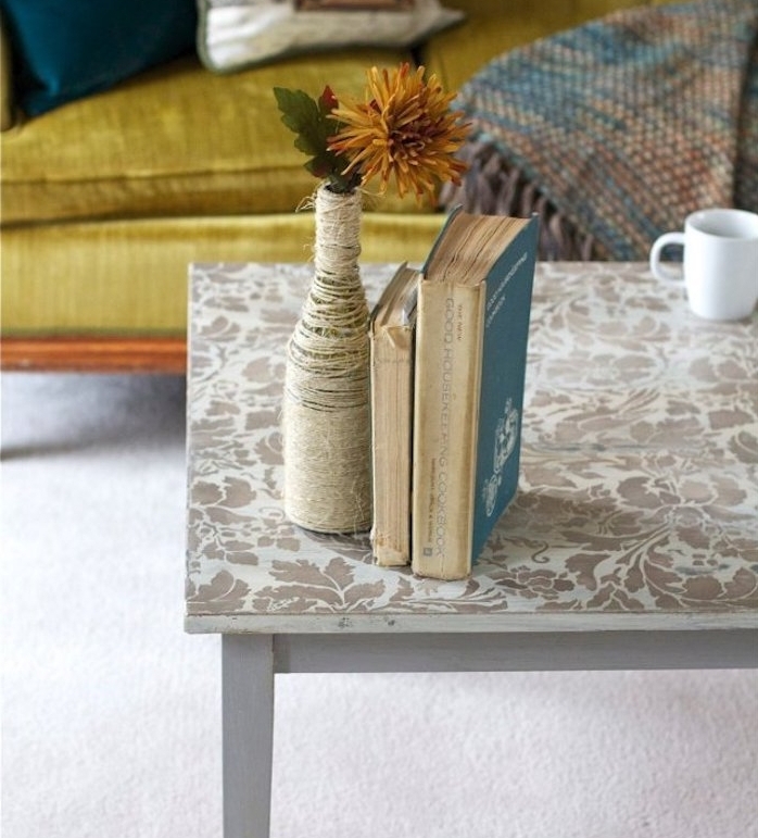 relooker une meuble, table décorée à motifs floraux créés au pochoir, livres, bouteille décorée de ficelle, canapé style oriental