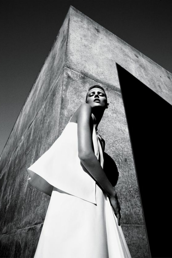 photo en noir et blanc, mannequin sur le fond d'un mur droit d'un grand édifice, femme en tunique blanche, paysage ensoleillé