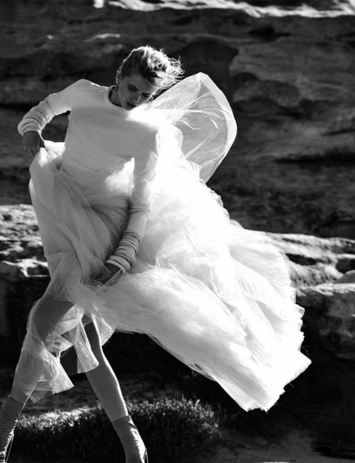 photo femme noir et blanc, danseuse dans la nature habillée en robe en tulle blanc, avec le vent qui joue avec la matière