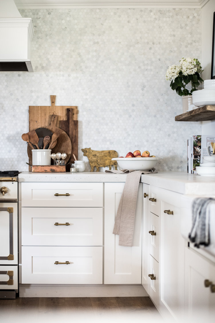 comment amenager une cuisine blanche avec des poignées vintage, plan de travail blanc, mur carrelage blanc et gris, etagere et planches à découper en bois